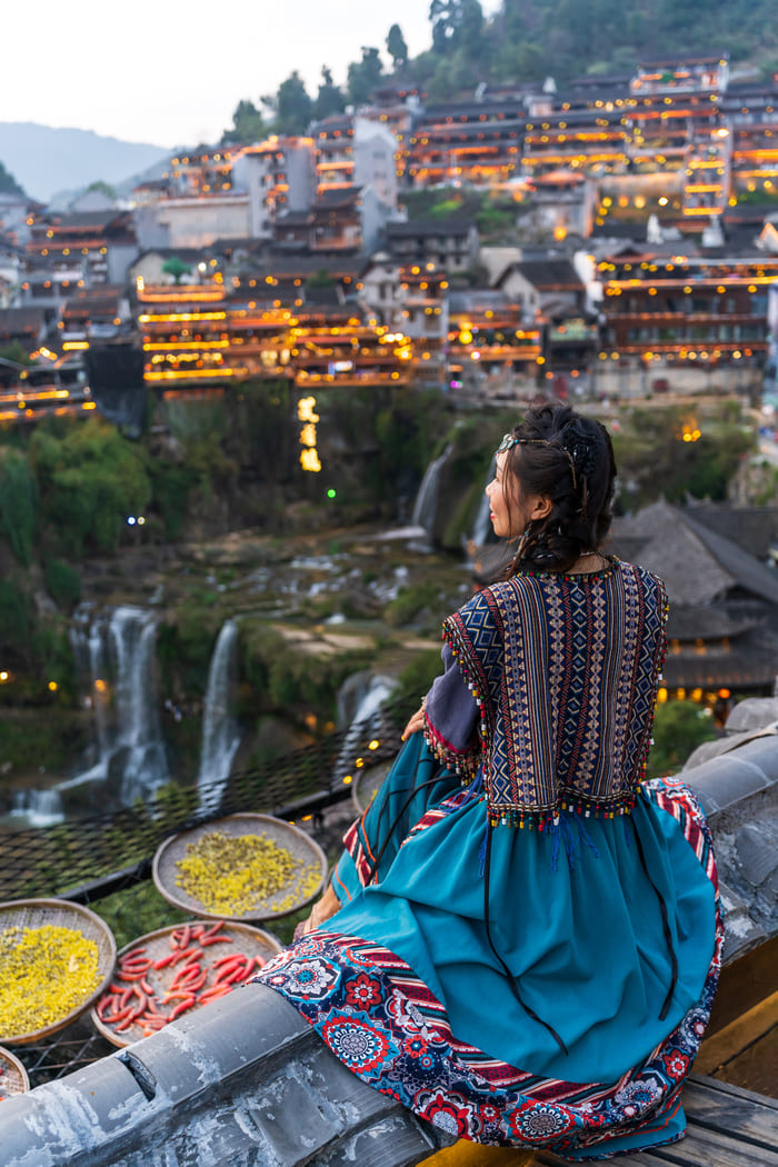 Mujer mirando al borde, con fondo de la ciudad de Lijiang
